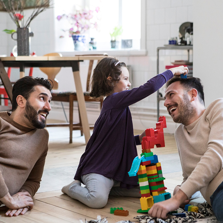 Young girl plays building blocks with her dads