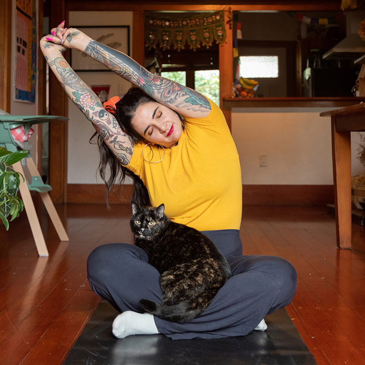 Woman doing yoga stretches with cat on her lap