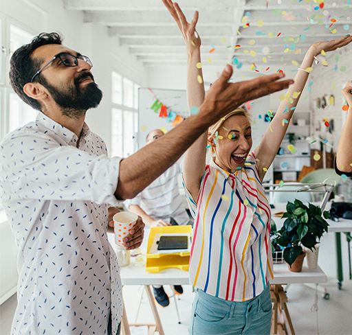 Coworkers throwing confetti in a bright modern office decorated for a party