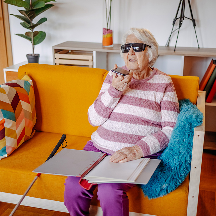 A blind woman talking on mobile phone while reading braille paperwork on a colourful lounge