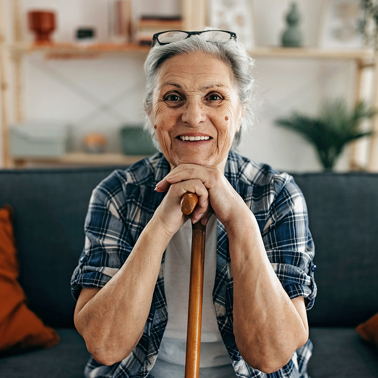 Smiling older Greek woman resting her hands on her cane