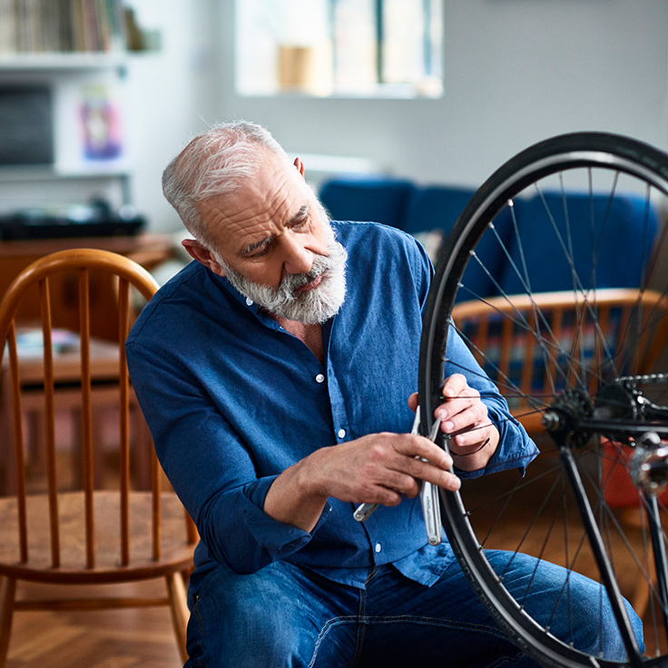 A stylish older man repairs his bicycle at home
