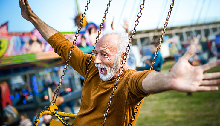 Older man riding swing at fair